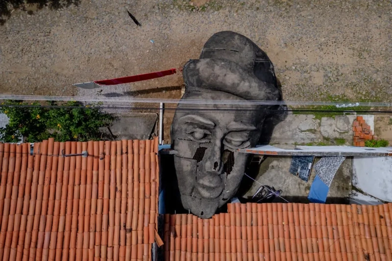 Cabeça de estátua gigante repousa em rua de cidade no interior do Ceará. Falando sobre o livro A Cabeça do Santo.