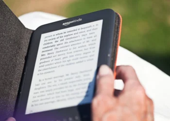 Pessoa manuseia o seu Amazon Kindle, que está protegido por uma capa preta. Falando sobre os melhores livros do Kindle Unlimited.